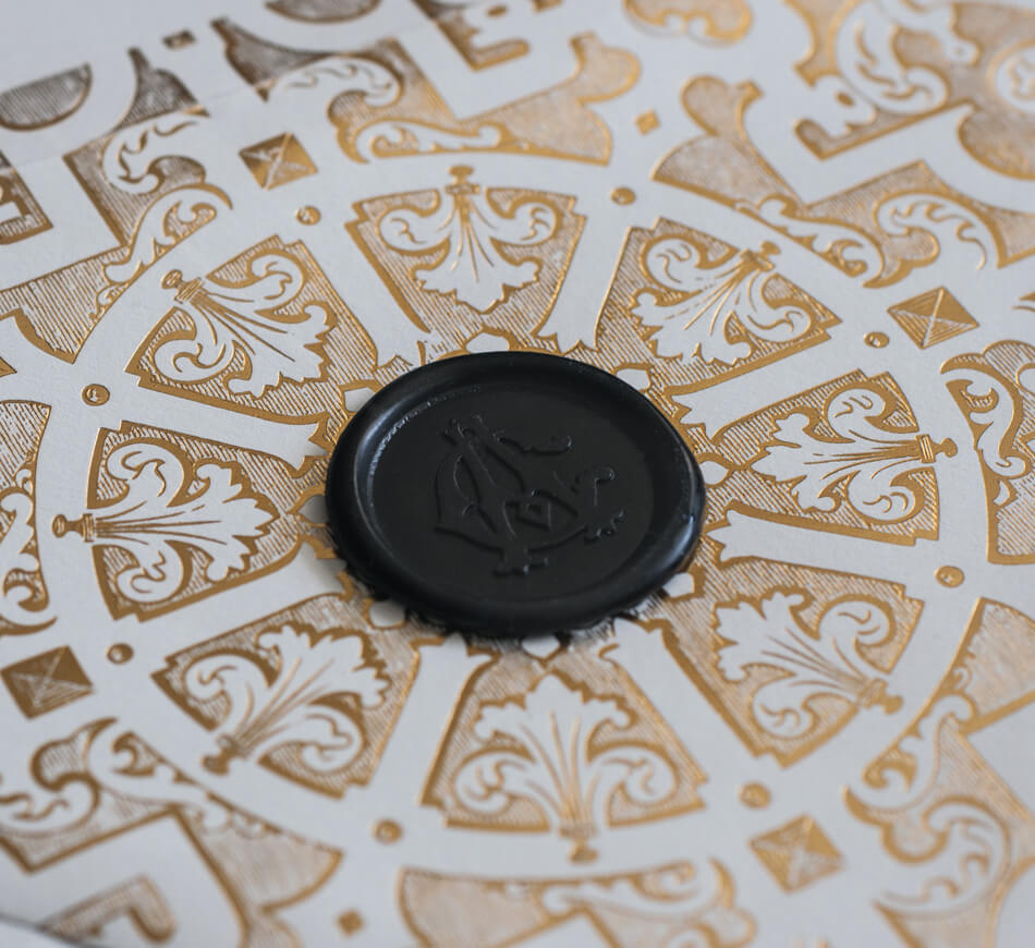 Black wax seal on gold and ivory envelope