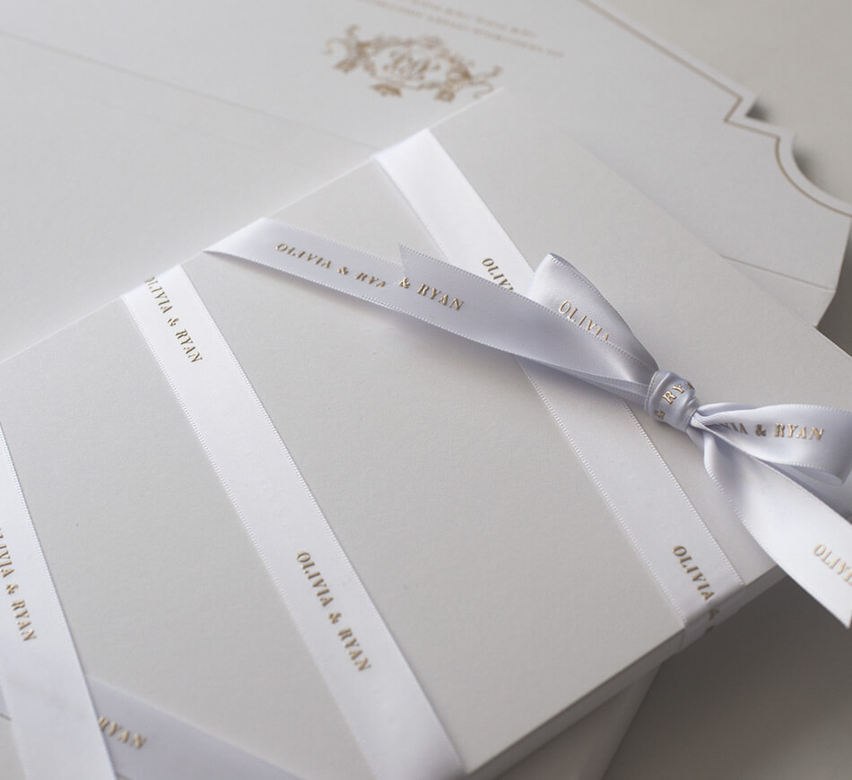 White and gold engraved ribbon wrapped around invitation